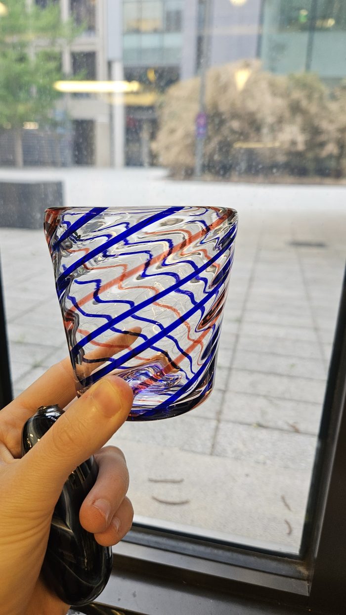 Clear glass cup with blue and red spiral stripes