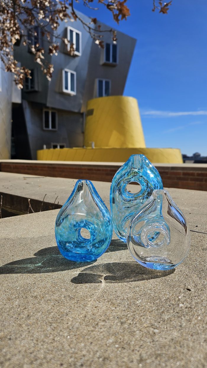 Three teal and clear glass vases with holes